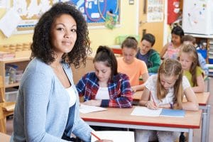 Lehrerin in der Klasse vor arbeitenden Schülern